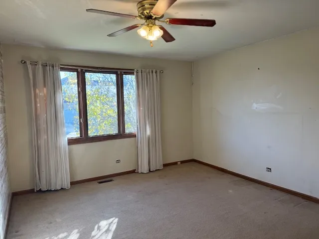 an empty room with windows and fan