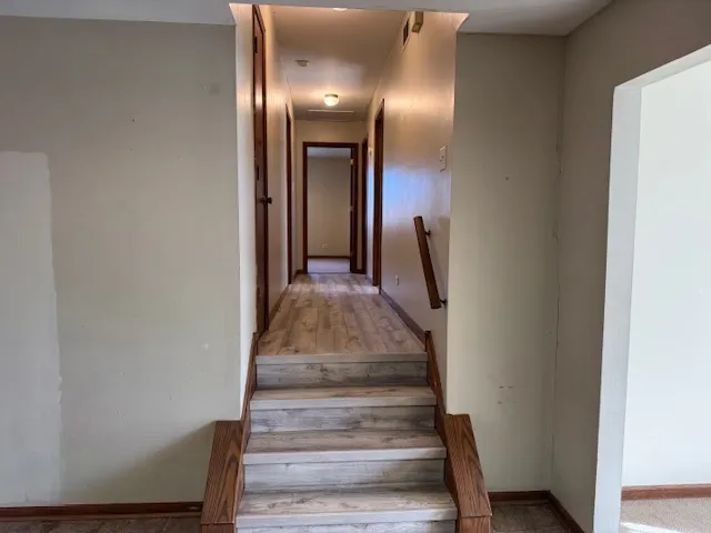 a view of a hallway with wooden floor and staircase