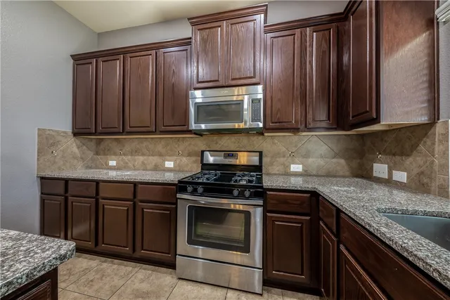 a kitchen with granite countertop wooden cabinets and stainless steel appliances