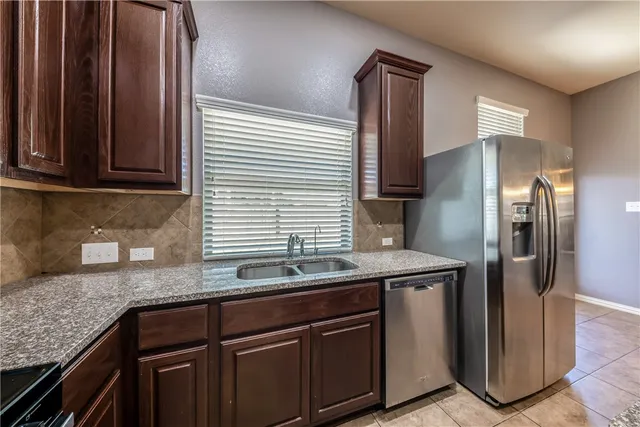 a kitchen with stainless steel appliances granite countertop a sink and a refrigerator