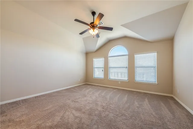 an empty room with chandelier fan and windows