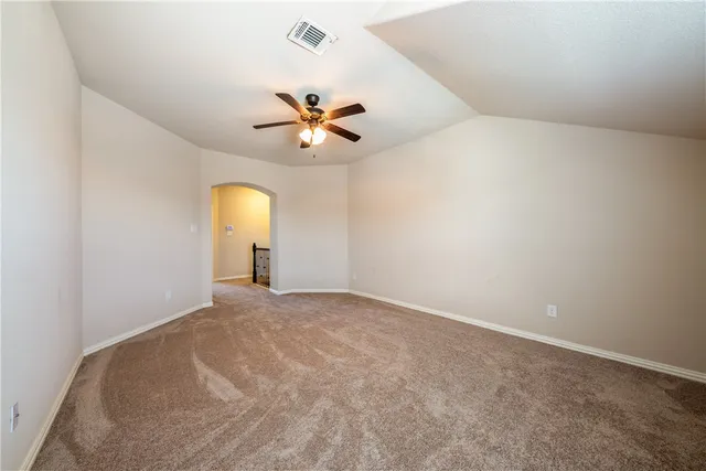 an empty room with chandelier fan and windows