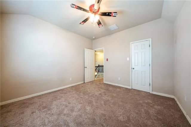 an empty room with closet and a ceiling fan
