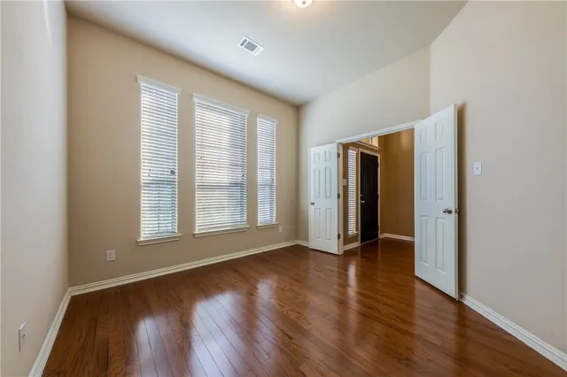 an empty room with wooden floor and windows