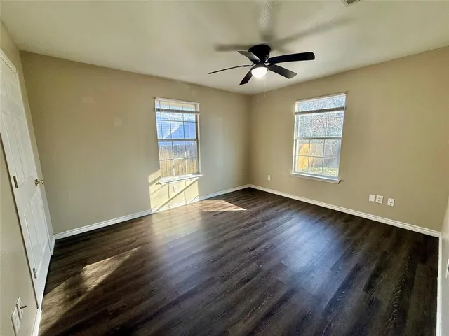 a view of empty room with wooden floor and fan