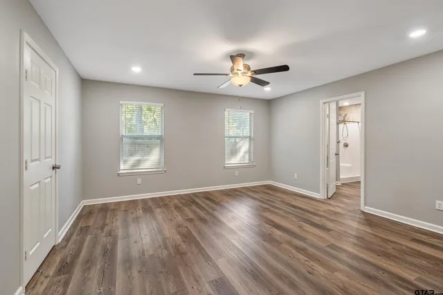 a view of empty room with wooden floor and fan