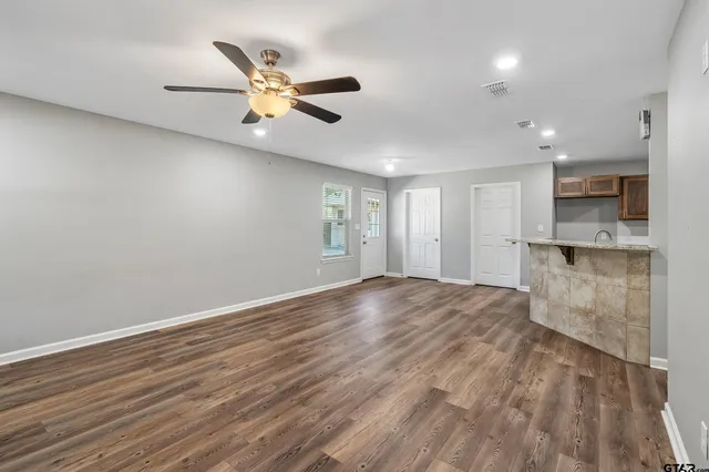 a view of an empty room with a window and wooden floor