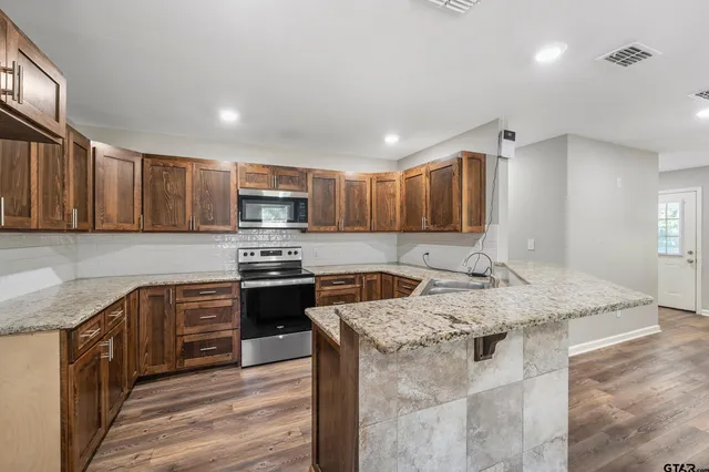 a kitchen with stainless steel appliances granite countertop a kitchen island hardwood floor sink stove and granite counter top