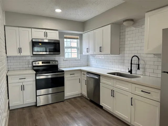 a kitchen with white cabinets stainless steel appliances and sink