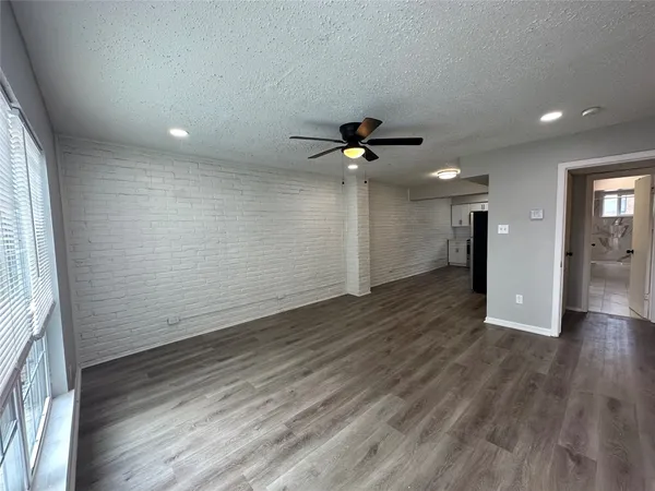 an empty room with wooden floor and a ceiling fan