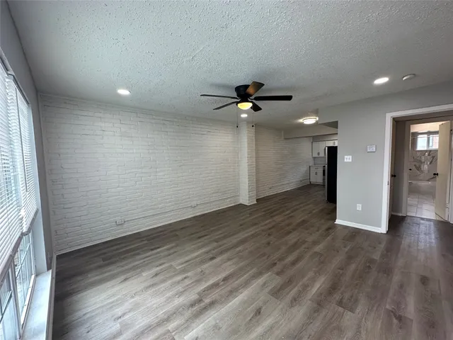 an empty room with wooden floor and a ceiling fan