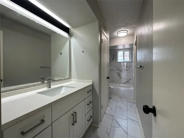 a bathroom with a granite countertop sink a toilet and shower