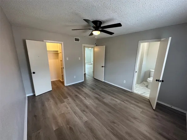 an empty room with wooden floor and a ceiling fan