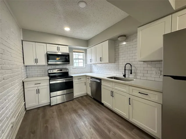 a kitchen with sink a microwave and cabinets