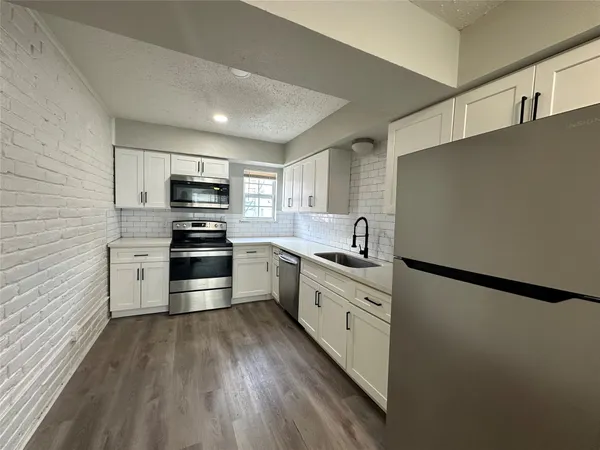 a kitchen with granite countertop a refrigerator stove and sink