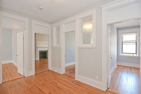 an empty room with wooden floor closet and windows
