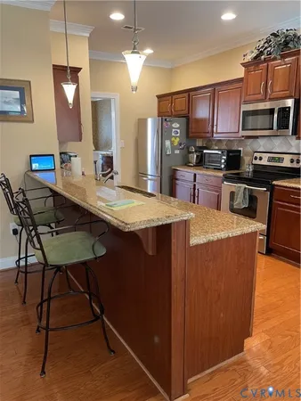 a large kitchen with kitchen island a wooden floor and stainless steel appliances
