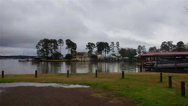 a view of a lake with a yard and large trees