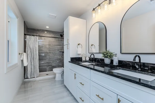 a spacious bathroom with a double vanity sink toilet and a mirror