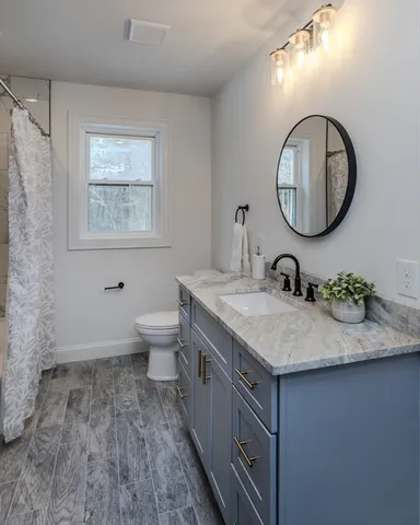 a bathroom with a granite countertop sink a toilet and a mirror