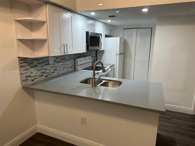 a kitchen with a sink a counter top space cabinets and appliances