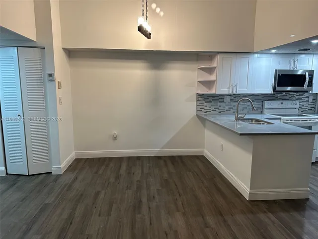 a view of kitchen with a sink wooden cabinets and window