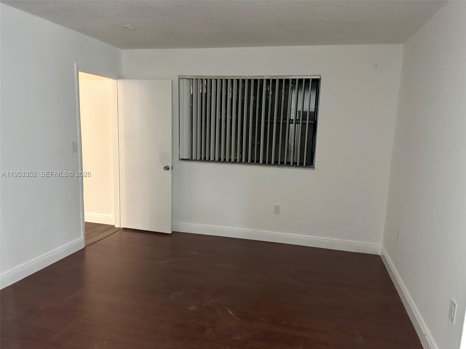 7155 Northwest 179th Street, Unit 304 Hialeah, FL 33015 - Photo 6 of 14 an empty room with wooden floor and windows