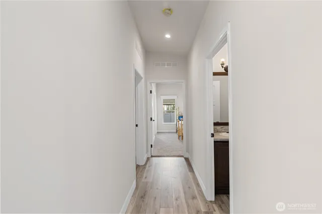 a view of a hallway with wooden floor and a bathroom