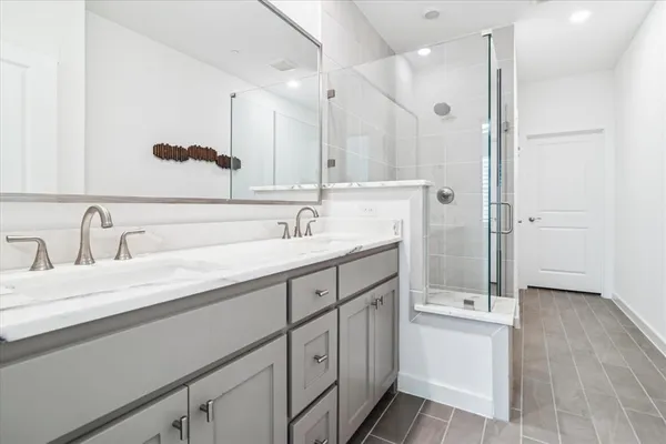 a spacious bathroom with a double vanity sink a mirror and shower