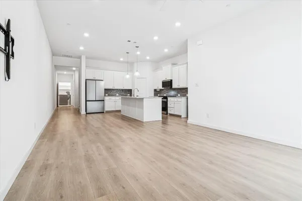 a view of kitchen with kitchen island stainless steel appliances refrigerator sink and cabinets