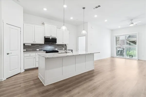 a large kitchen with cabinets wooden floor and a view of living room