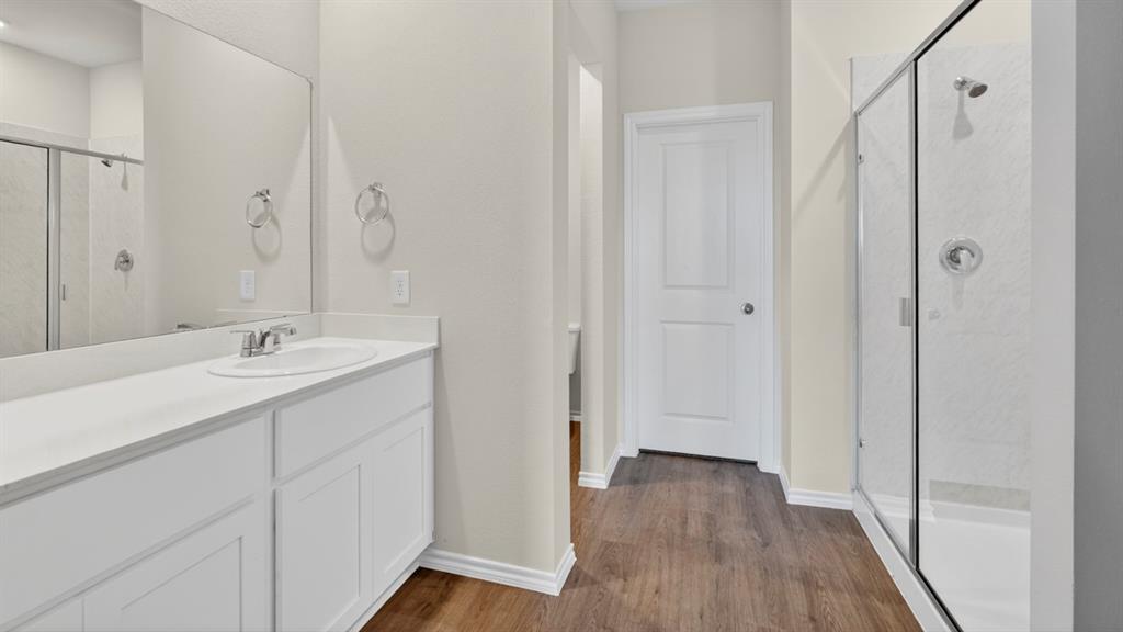 1683 Mantle Road Crandall, TX 75114 - Photo 20 of 31 Contemporary bathroom featuring a single vanity with an integrated sink, white cabinetry, a large frameless mirror, and a glass-enclosed shower with a tiled surround