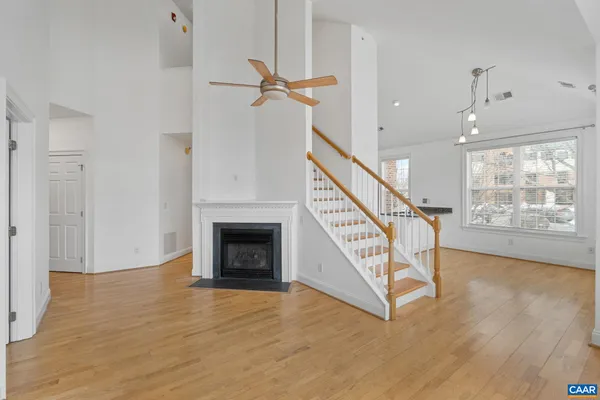 a view of an empty room with wooden floor a ceiling fan and windows