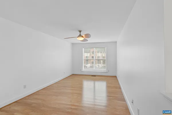 a view of an empty room with wooden floor and a window