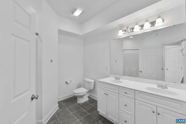 a spacious bathroom with double sink a toilet a shower and a mirror