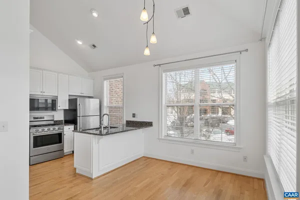 a kitchen with kitchen island white cabinets and stainless steel appliances