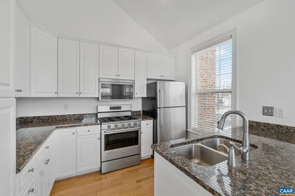 a kitchen with granite countertop white cabinets and stainless steel appliances