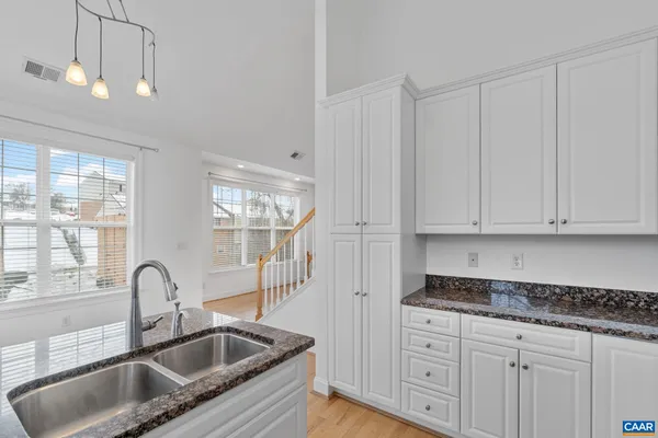 a kitchen with granite countertop white cabinets and sink