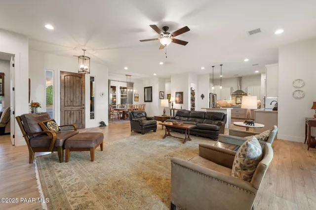 a kitchen with stainless steel appliances kitchen island granite countertop a refrigerator oven and white cabinets with wooden floor