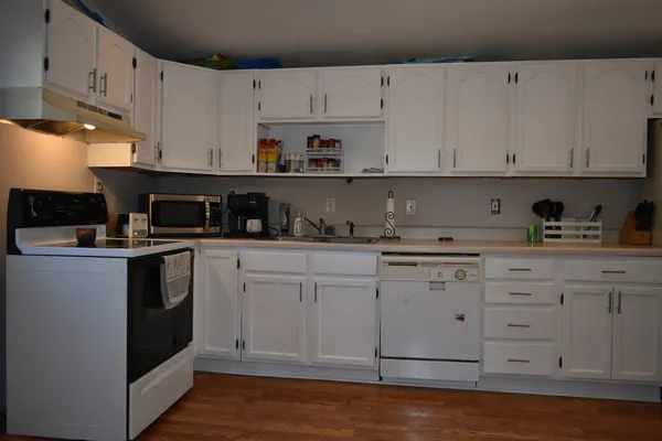 a kitchen with granite countertop white cabinets and white appliances