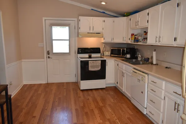 a kitchen with cabinets wooden floor and stainless steel appliances