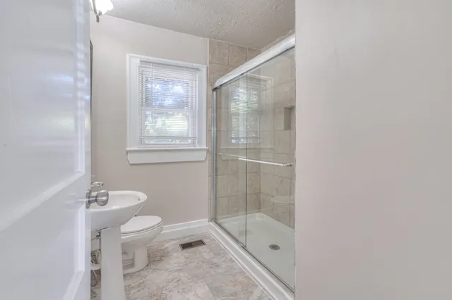 a bathroom with a granite countertop sink a toilet and shower