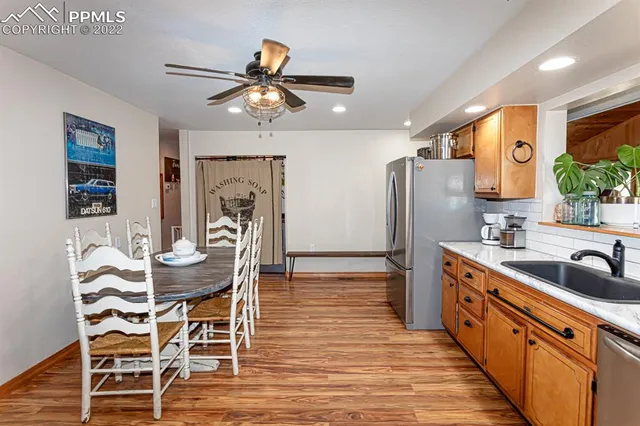 a kitchen with stainless steel appliances granite countertop a refrigerator a stove a sink a dining table and chairs with wooden floor