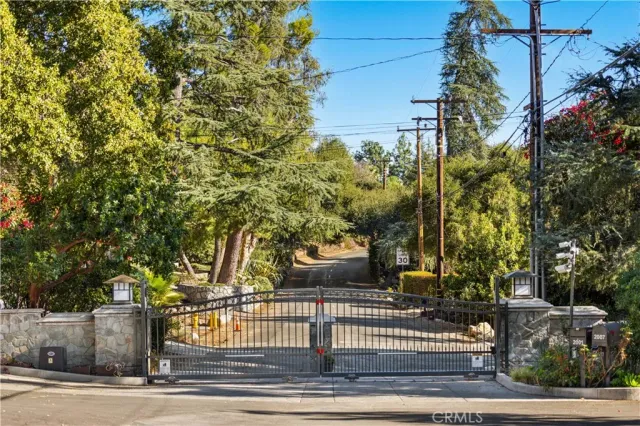 a view of a brick house with large trees and wooden fence