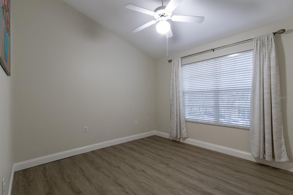 10000 Southwest 52nd Avenue, Unit 60 Gainesville, FL 32608 - Photo 18 of 36 an empty room with wooden floor fan and windows