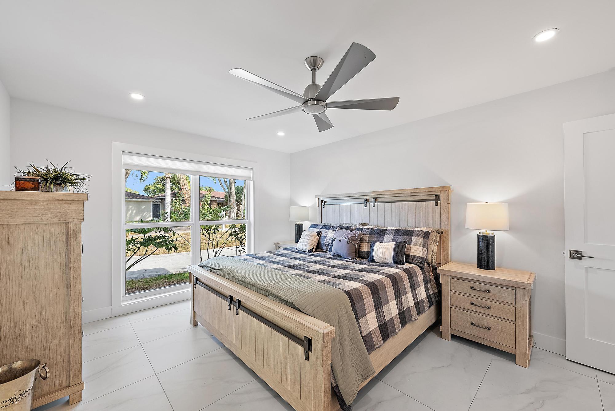 9524 Southeast Cove Point Street Jupiter, FL 33469 - Photo 11 of 35 a bedroom with a large bed and a chandelier