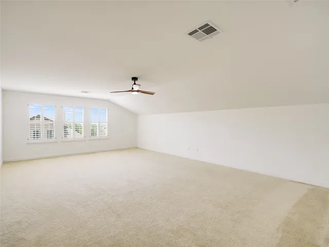 an empty room with a ceiling fan and windows