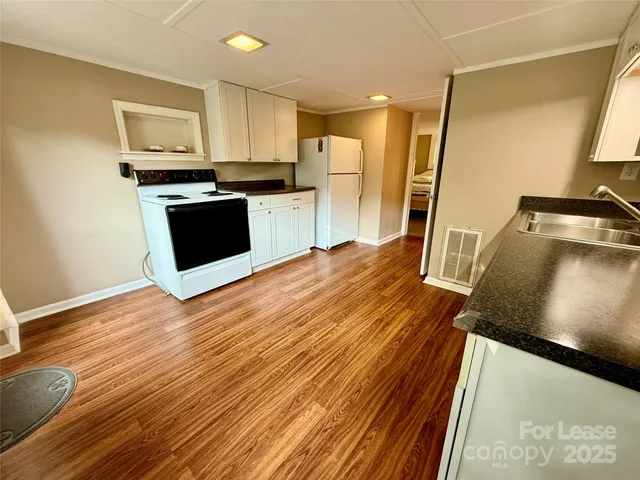 a kitchen with stainless steel appliances a stove top oven a refrigerator a sink and dishwasher with wooden floor