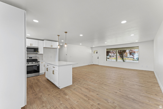 1898 West 600 South Provo, UT 84601 - Photo 9 of 32 Open-concept living space featuring wood-finish flooring, recessed lighting, and a kitchen island with pendant lighting