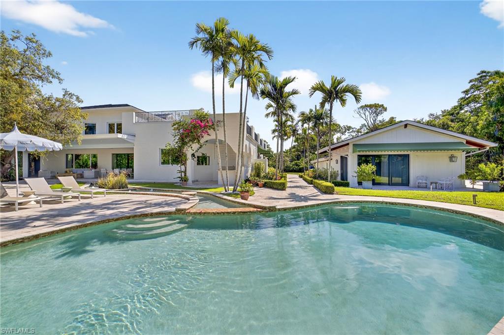 111 Caribbean Road Naples, FL 34108 - Photo 1 of 50 a front view of a house with swimming pool having outdoor seating